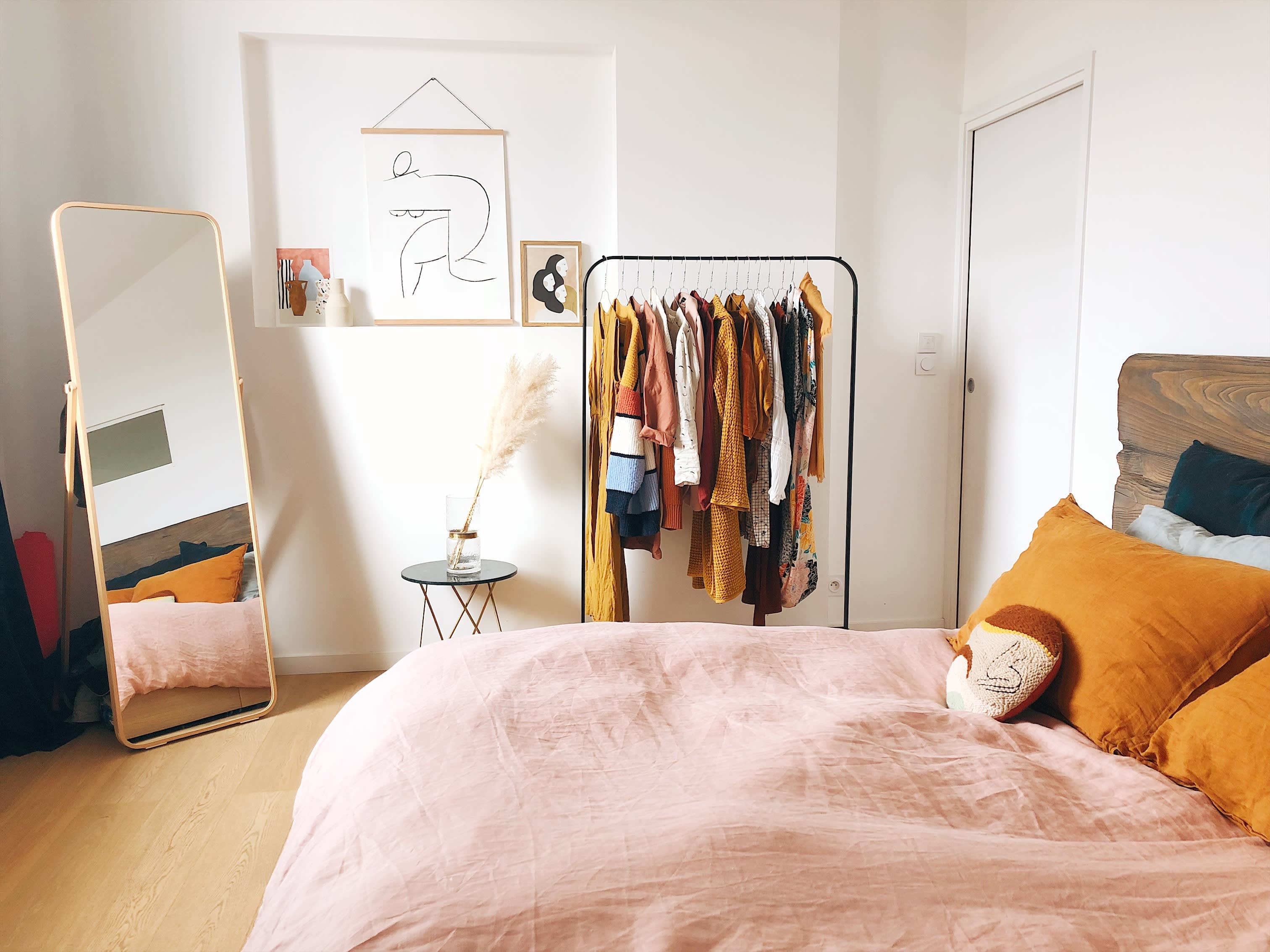 Schlafzimmer mit einem Bett, Kleiderstange und Spiegel