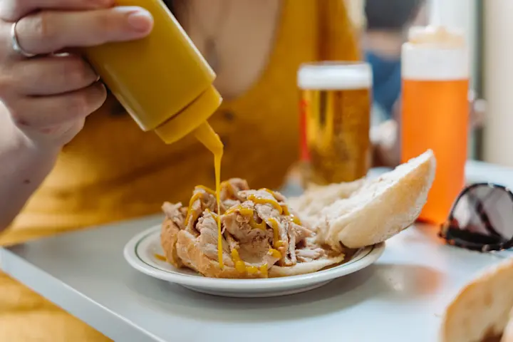 Dripping sauce onto a bifana sandwich in Lisbon.