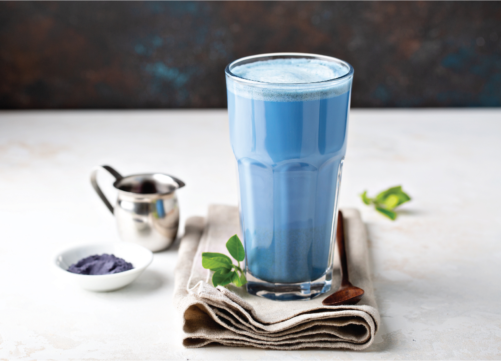 An image of a Blue Lavender latte in a glass sat on a napkin