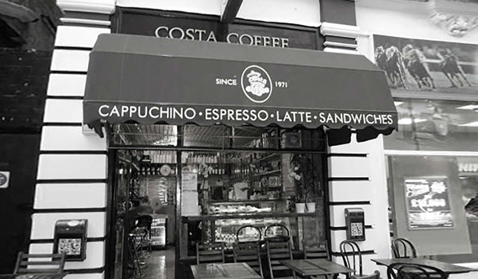Black and White photo of the outside of the original costa coffee shop on the Vauxhall Bridge Road in London.
