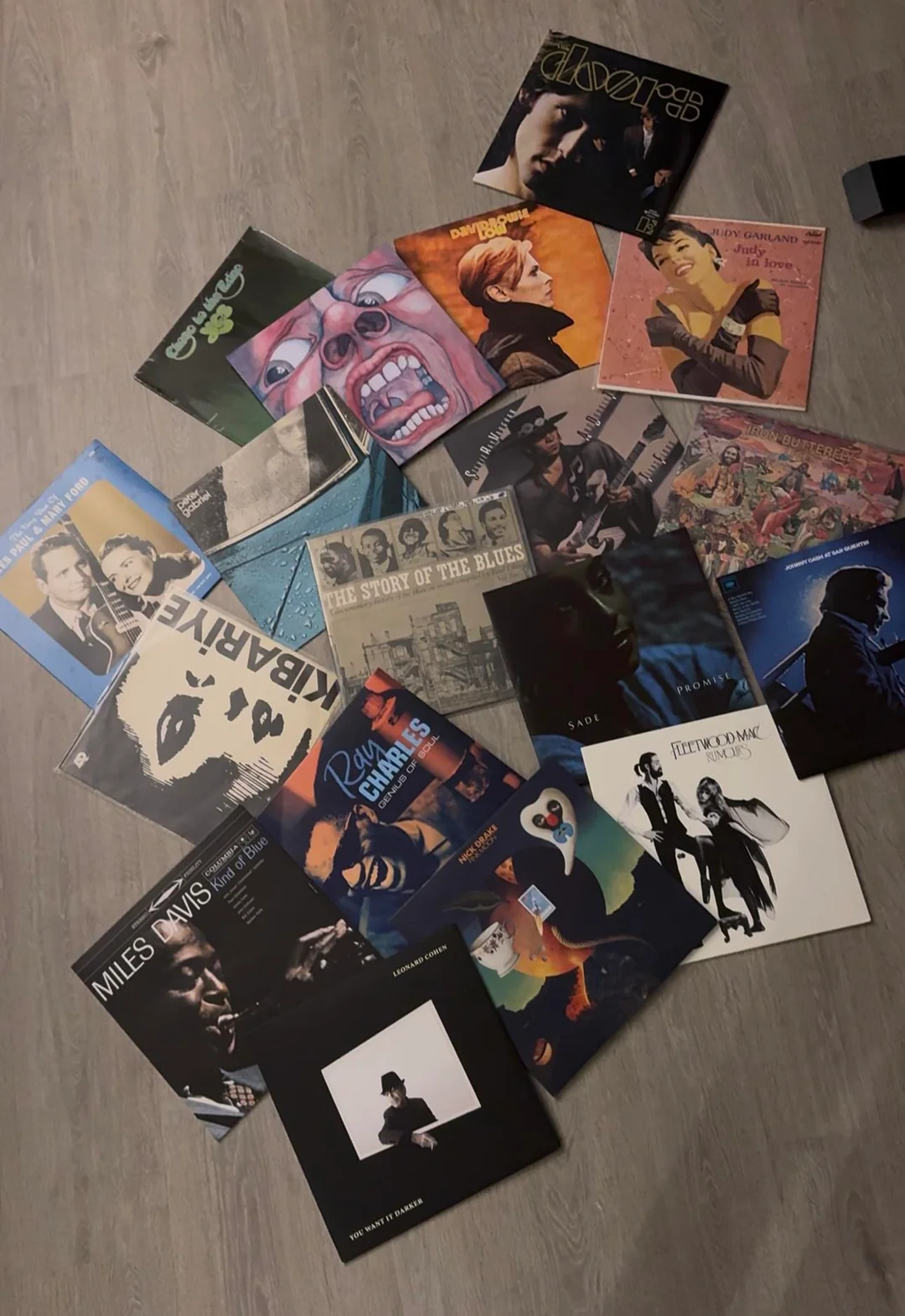 Vinyl records by artists including David Bowie, King Crimson, Miles Davis, Judy Garland and Fleetwood Mac are arranged across a wooden floor.
Caption: The collection so far: art rock at its centre, with jazz, blues and several beautiful detours.