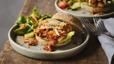 Two plates of Sloppy Joes, with salad garnish, on a wooden table.