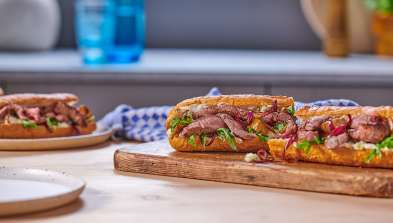 Stilton and Pear Steak Sandwich landscape shot of open sandwich on wooden chopping board within a kitchen scene.