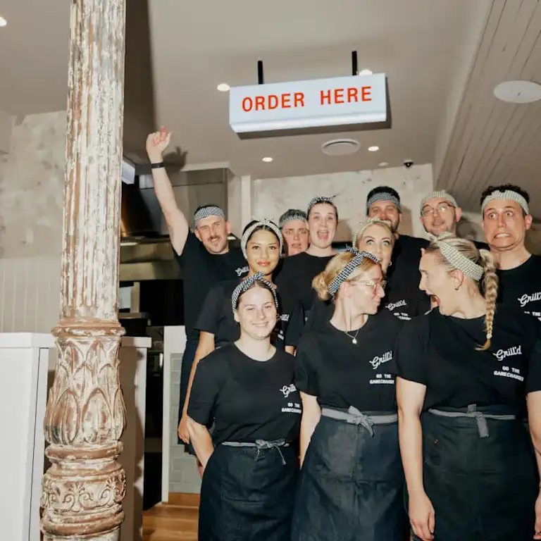 A group of young Grill'd team members wearing aprons and bandanas 