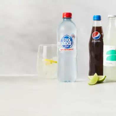 Three bottles of drinks with a glass with a lemon drink.