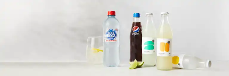 Four bottles of drinks with a glass with a lemon drink.