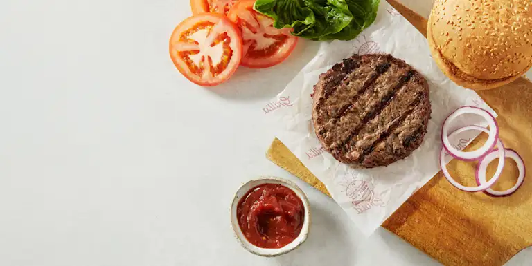Sliced tomatoes, beef pattie and bacon slices on a background