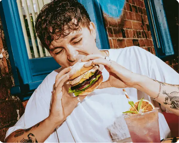 Young guy taking a bite out of a grilled chicken burger