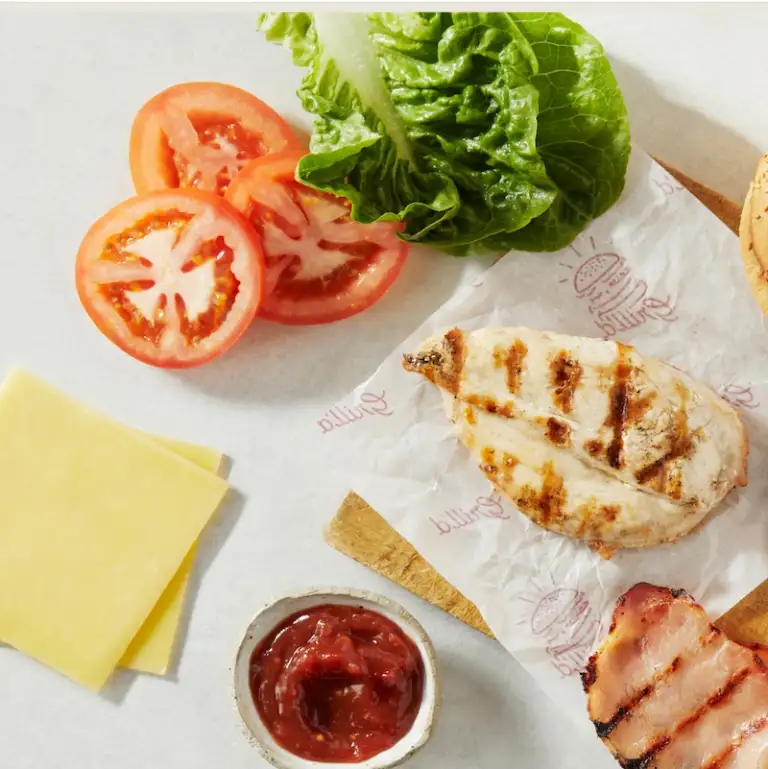 Spread of grilled chicken breast, bacon, tasty cheese, sliced tomato and lettuce