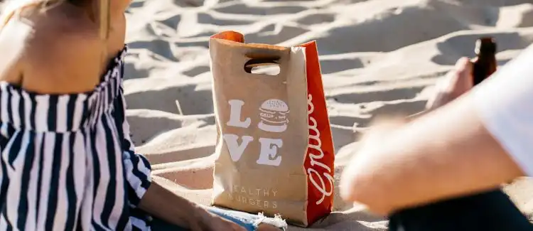 Grill'd takeaway bag on beach with couple