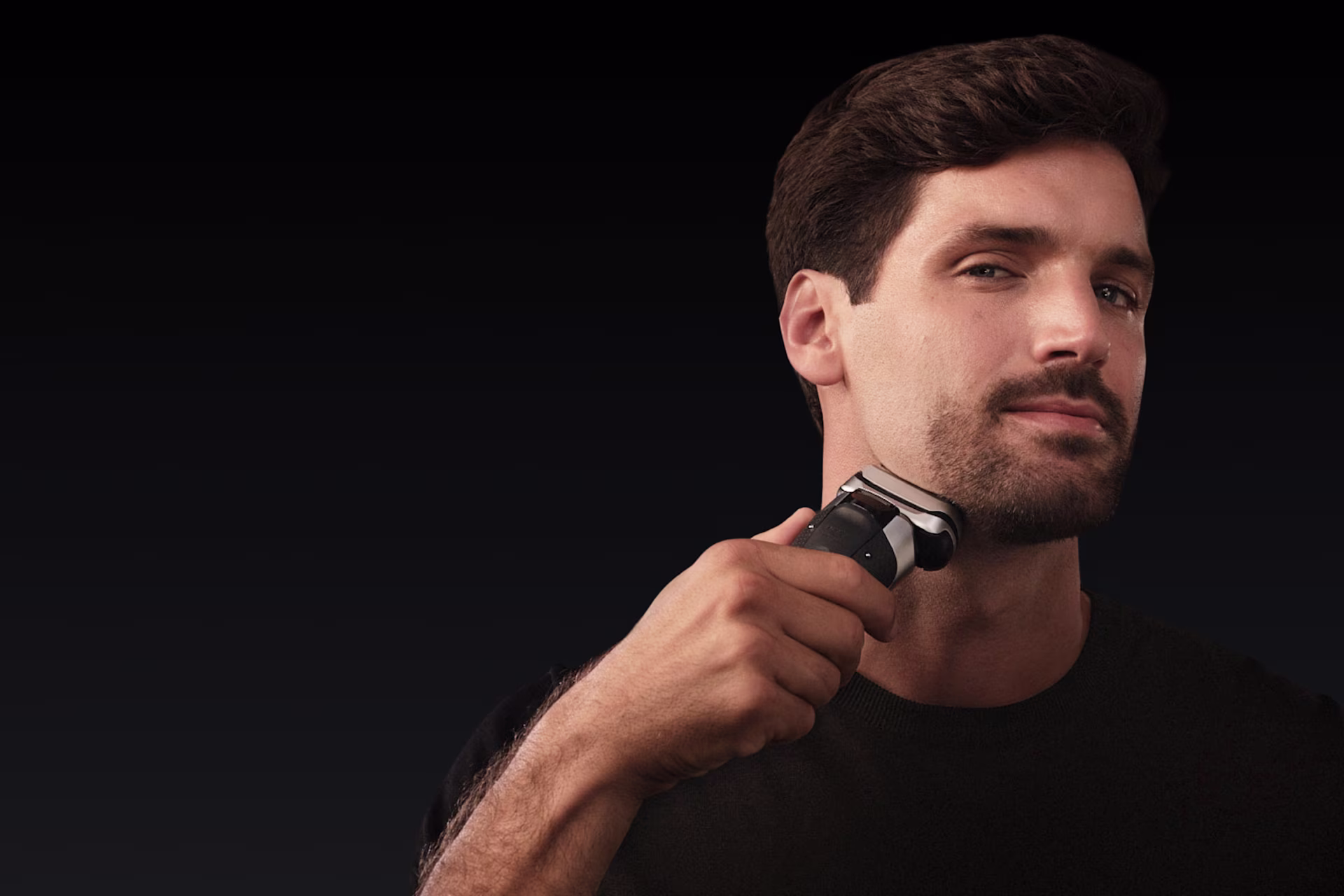 Κοντινό πλάνο ενός άνδρα που χρησιμοποιεί την ηλεκτρική ξυριστική μηχανή Braun Series 9 Pro+ στο πηγούνι του σε σκοτεινό φόντο. Η εικόνα δείχνει την ευελιξία της ξυριστικής μηχανής να φτάνει σε δύσκολες περιοχές. Κοντινό πλάνο ενός άνδρα που χρησιμοποιεί την ηλεκτρική ξυριστική μηχανή Braun Series 9 Pro+ στο πηγούνι του σε σκοτεινό φόντο. Η εικόνα δείχνει την ευελιξία της ξυριστικής μηχανής να φτάνει σε δύσκολες περιοχές.