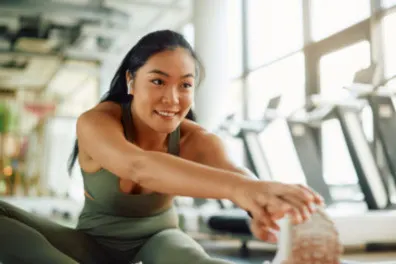 Smiling athlete stretching her leg