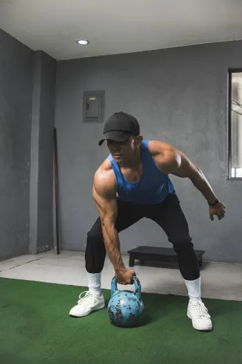 A fit muscular guy prepares to do a set of single arm shoulder thrusters