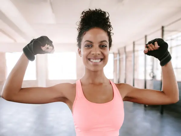 ISSA trainer smiling while flexing biceps