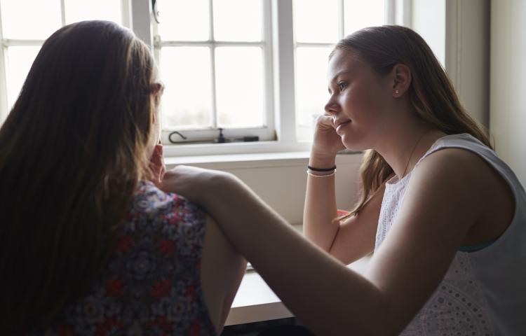 Girl comforting a friend indoors