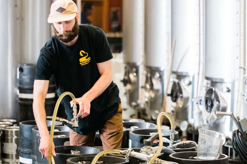 A brewer filling a barrel with beer at Blackfoot River Brewing