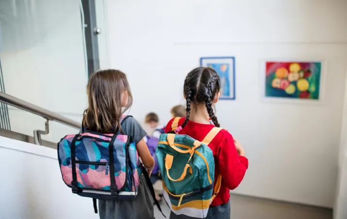 Two primary school students walking in the corridor after a lesson with their teacher