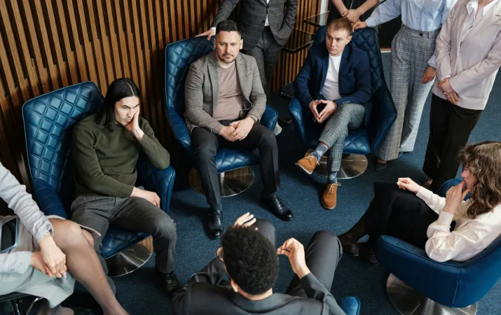 A large group of lawyers sitting in a circle during a meeting discussing a legal matter