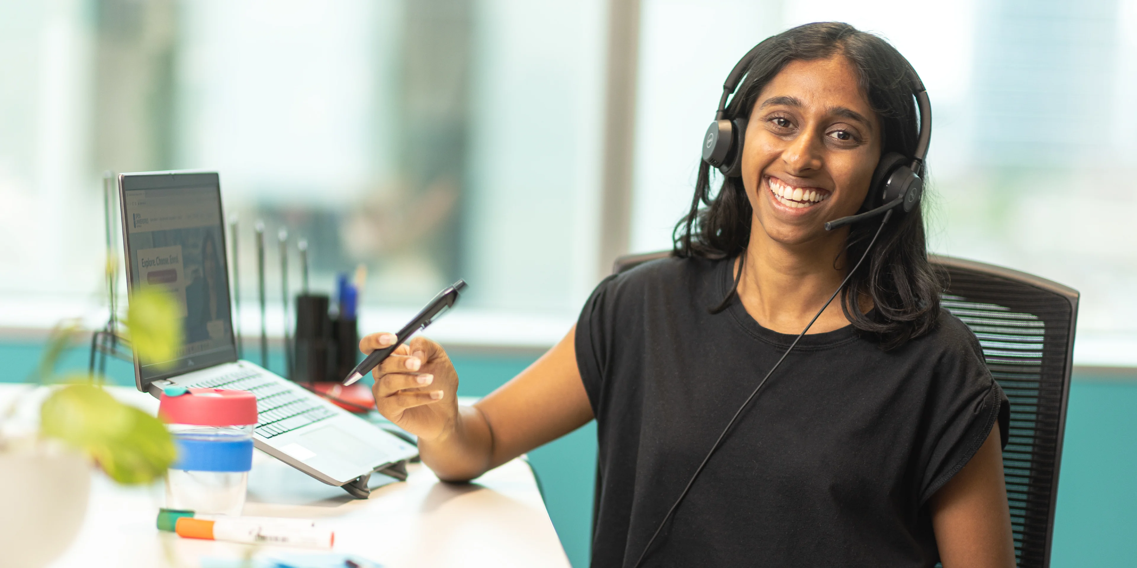 Giselle, a smiling student advisor wearing a headset at her workstation, ready to help with student questions.