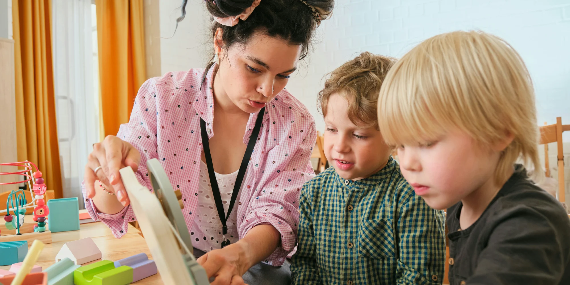 An early childhood teacher showing two young boys shapes and concepts at a long daycare centre