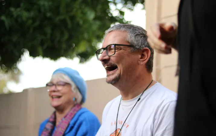 A jubilant older male counsellor standing outdoors in a circle with a female colleague