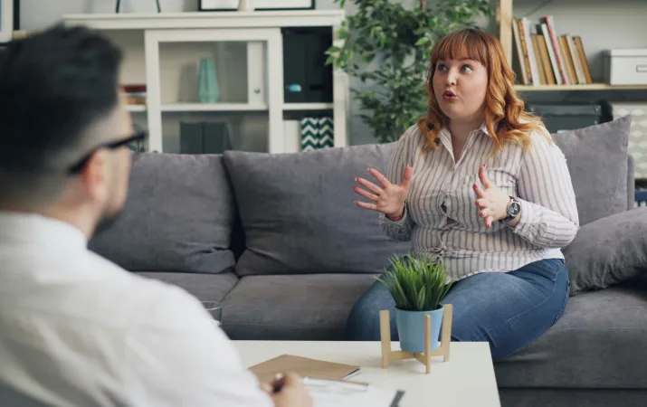 Woman with red hair uses hands to explain situation.
