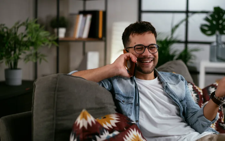 A man laughing on the phone as he seeks out university support for his psychology course