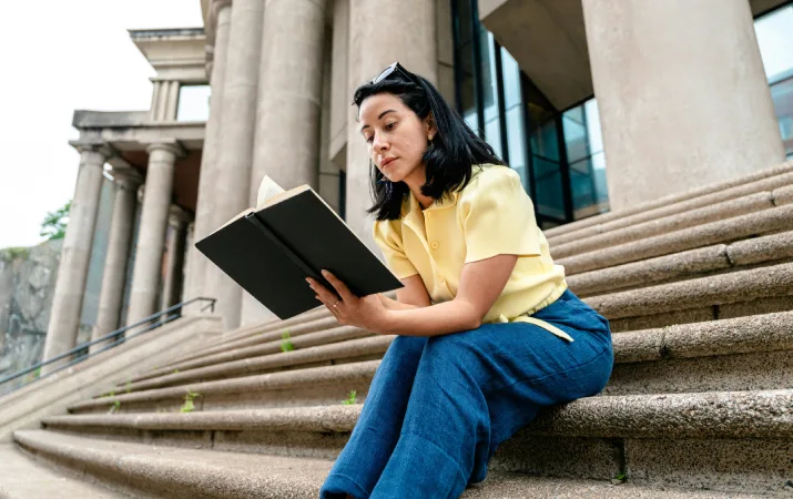Law student studying on stone steps reading a book