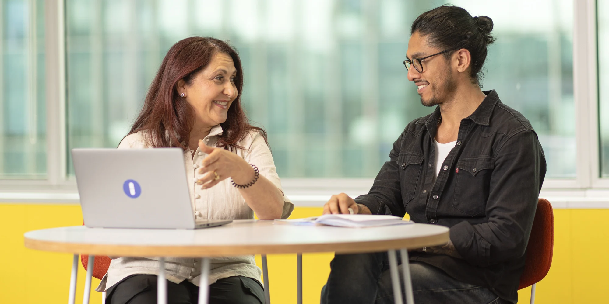 Two happy Open Universities Australia professionals chatting in a bright office space