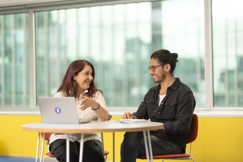 Maria and Eduardo smiling and chatting in a bright office space