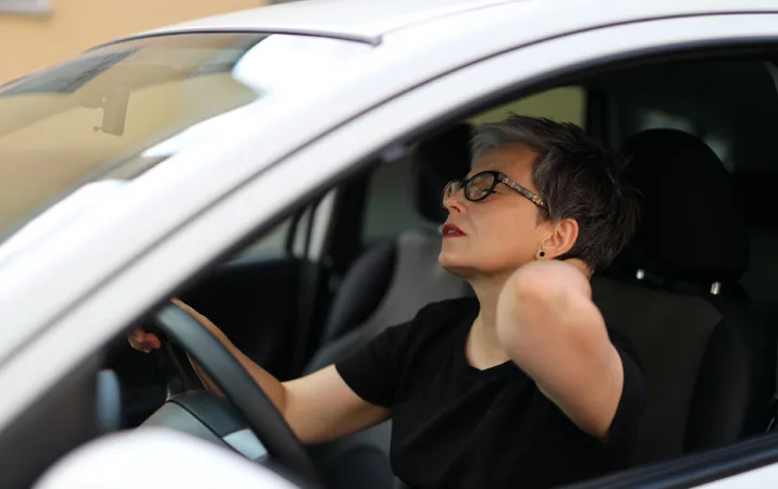 A tired older woman sitting behind the wheel of a car