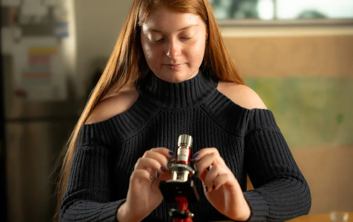 OUA student Sophie looking down at a microscope