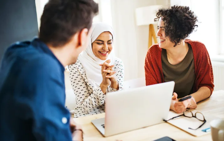A multicultural group sitting around a laptop