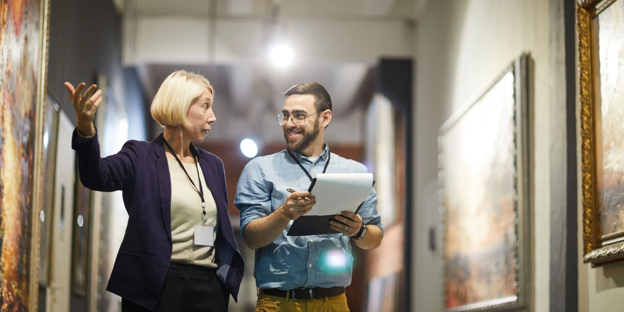 Museum curators collaborating on an exhibition of historical paintings.