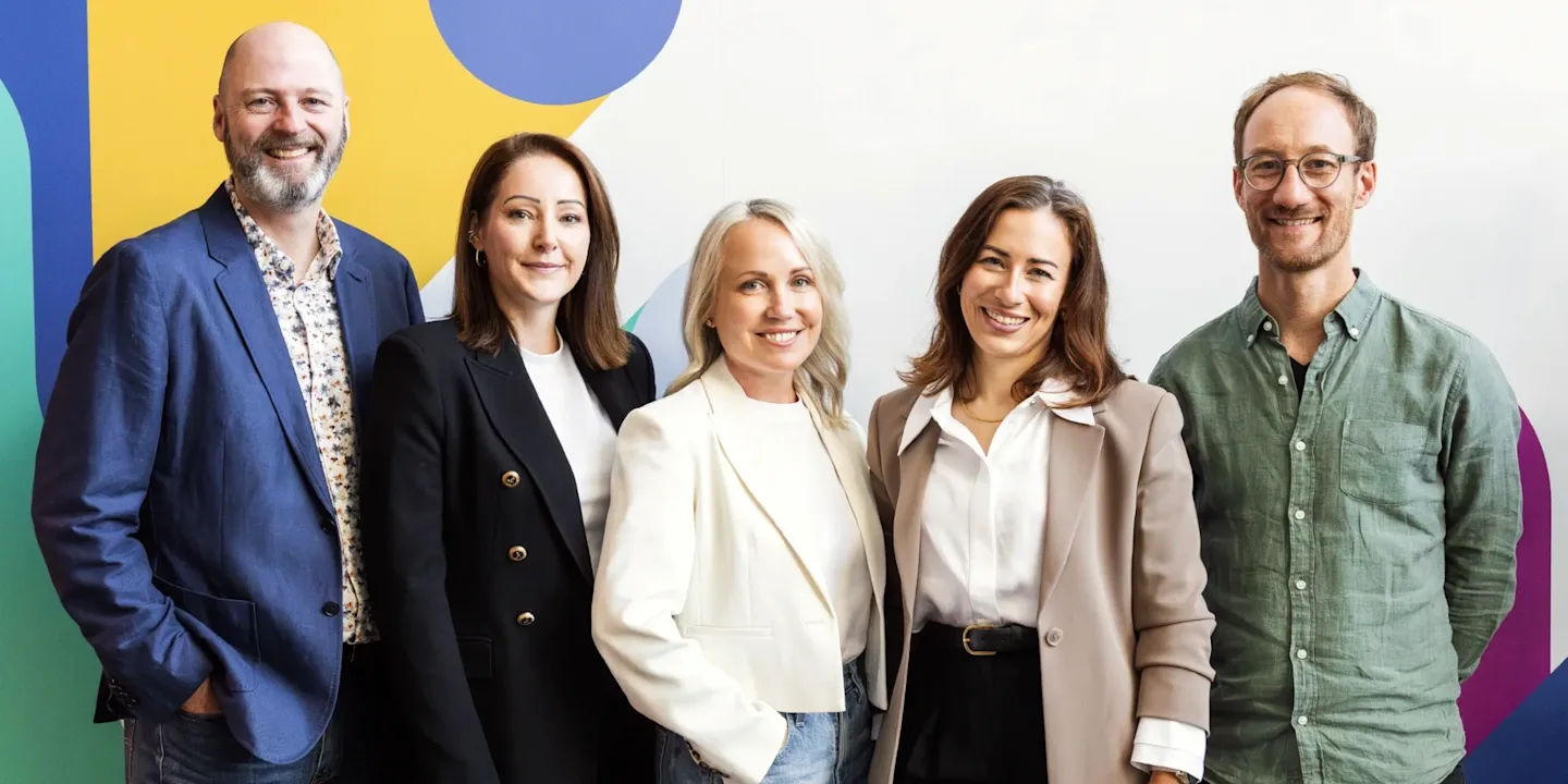 A group of smiling professionals standing against a vibrant backdrop.