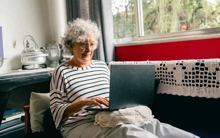 Person using a laptop on their lap while seated at home.