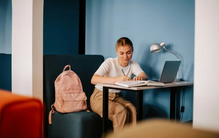 A Year 12 student sitting in a booth with her laptop planning her pathway into psychology study at university
