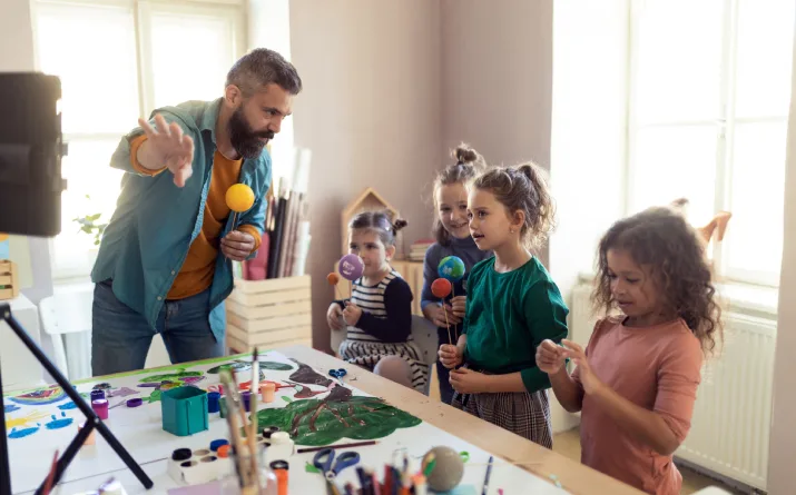 A male artist teaching four young children