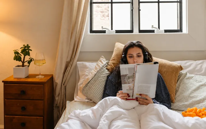 Woman wearing headphones and reading study materials from home.