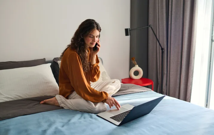 Casual young woman on laptop requesting help on phone