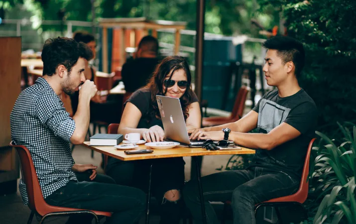 Three students studying together in an outdoor cafe