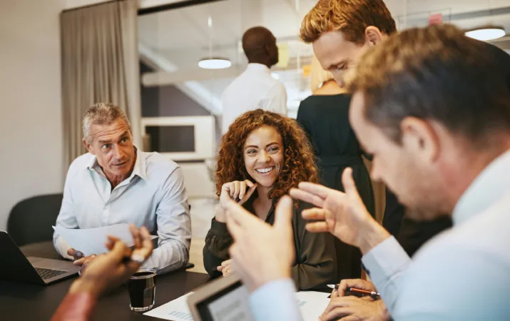 A group of human resource professionals smiling and listening intently to a man using his psychology knowledge to make a convincing point