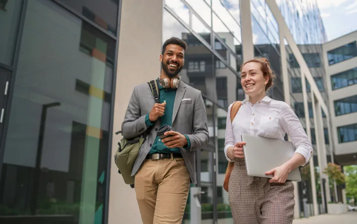 Two provisional psychologists smiling as they walk into work together outside a city building
