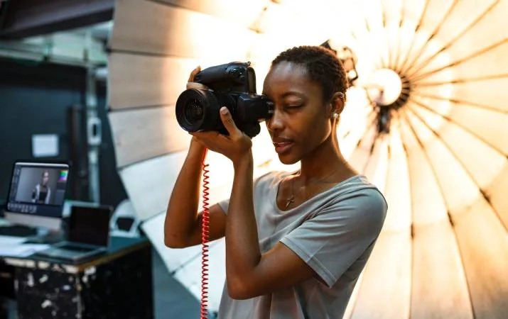 A photographer at work in front of a reflective umbrella, with a computer screen behind her to demonstrate her technical range of skills