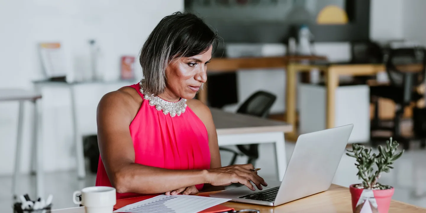 A professional in deep-focus on a laptop, upskilling for advancement in a modern office.