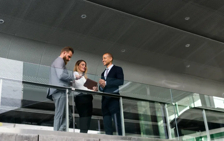 Three lawyers standing on a balcony inside a legal office.