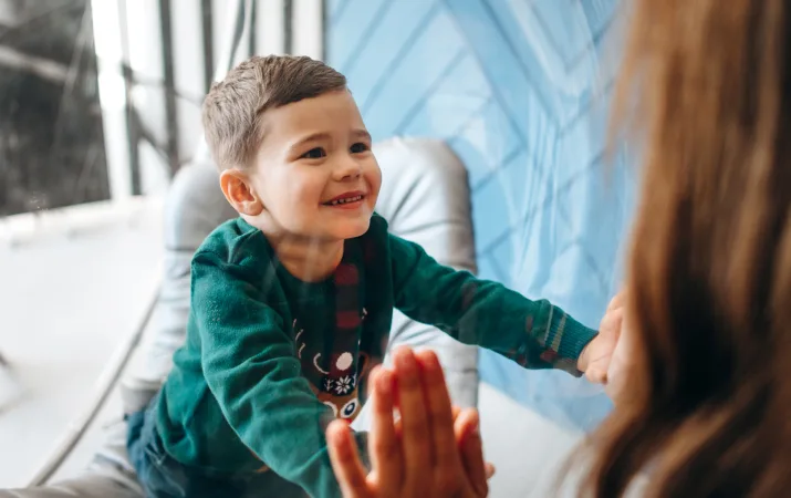 A smiling child doing exercises with an early intervention specialist, who helps children with additional needs