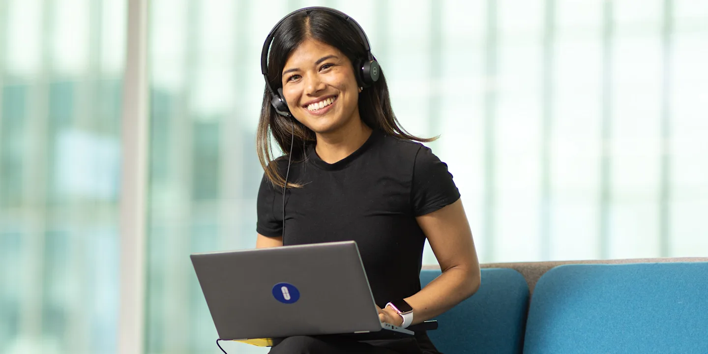 Natcha, a smiling student advisor wearing a headset at her workstation, ready to help with student questions.