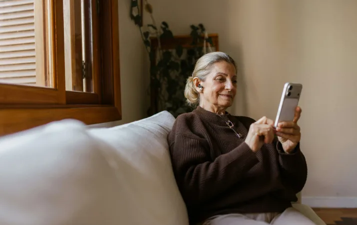 Older woman smiling as she reviews her university application on her phone