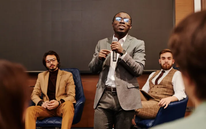 A leader in business presenting confidently at a panel with the people skills gained during his psychology course